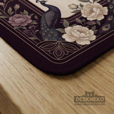 Square mahjong mat with a dark plum border, ivory floral pattern, muted sage leaves, and a decorative peacock garden design.