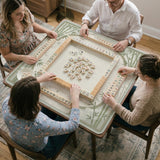 Square mahjong table mat with a pale cream center and green bamboo chinoiserie corners and border.