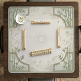 Square mahjong table mat with a pale cream center and green bamboo chinoiserie corners and border.
