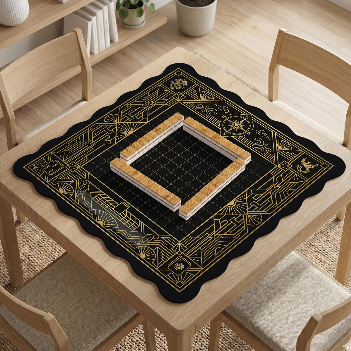 Black and gold square mahjong mat with a scalloped edge, geometric border, thin line details, fan motifs, and dragon and phoenix accents around an open center.