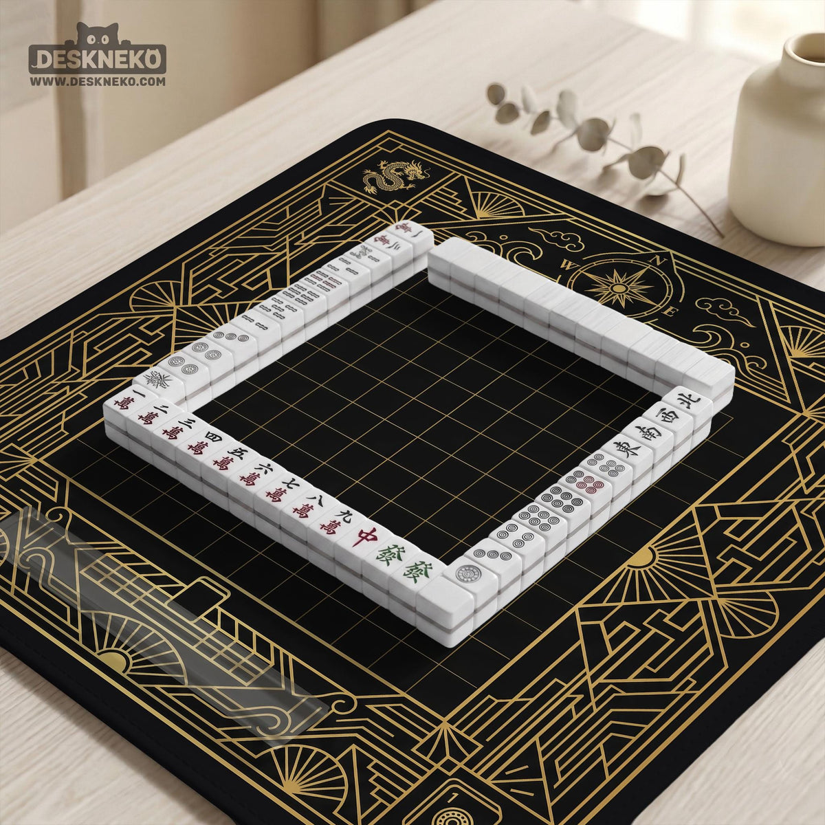Black and gold square mahjong mat with a scalloped edge, geometric border, thin line details, fan motifs, and dragon and phoenix accents around an open center.