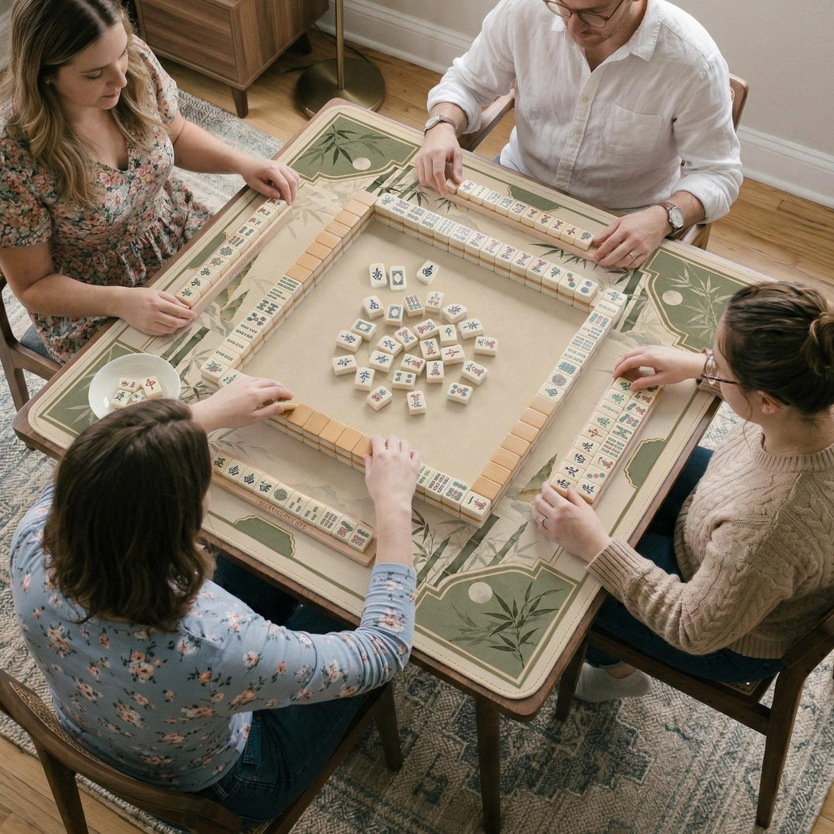 Square mahjong mat with a sage green bamboo and mountain design, cream center, scalloped border details, and gold line accents.