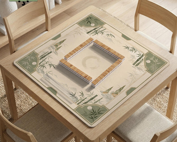 Square mahjong mat with a sage green bamboo and mountain design, cream center, scalloped border details, and gold line accents.