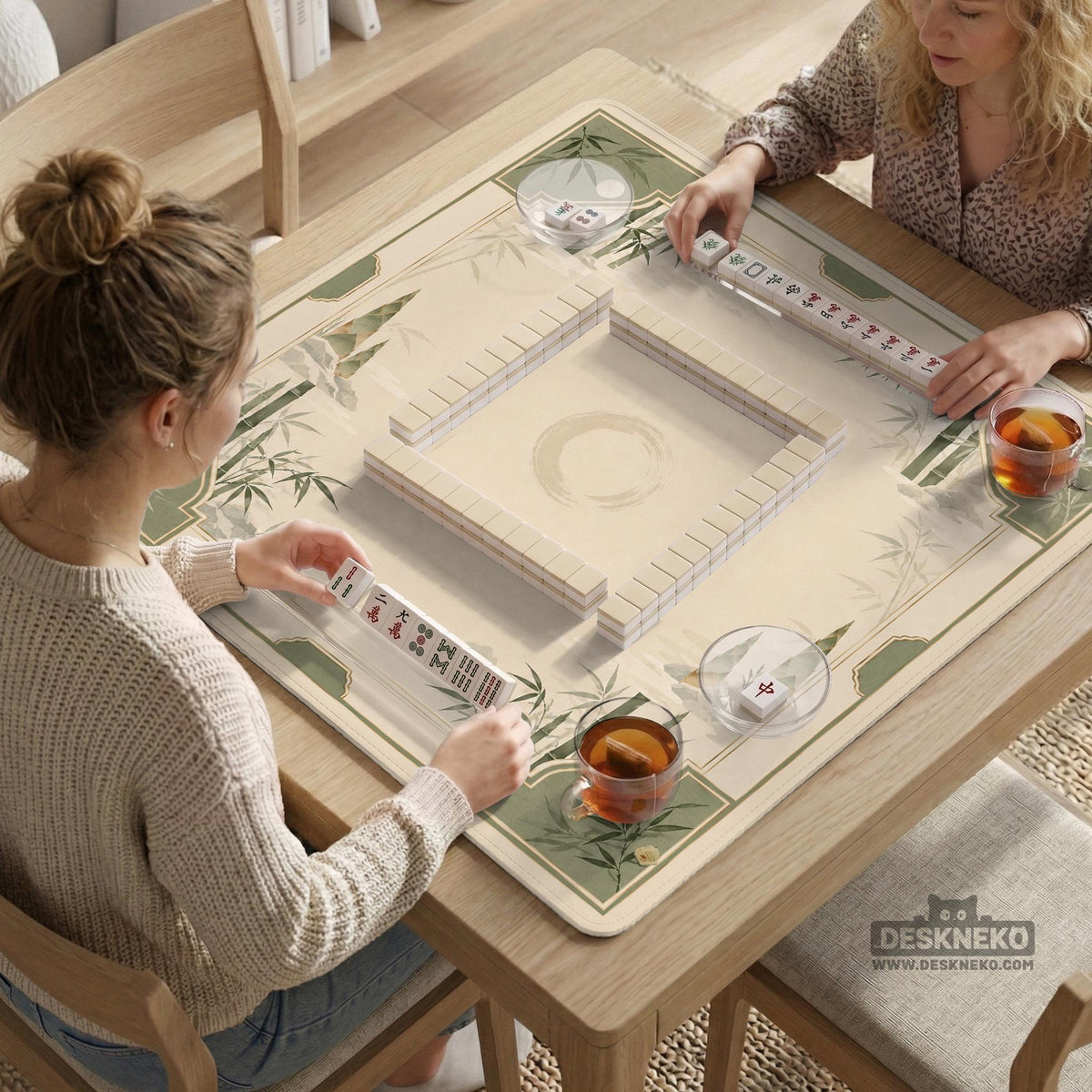 Square mahjong mat with a sage green bamboo and mountain design, cream center, scalloped border details, and gold line accents.