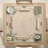 Square mahjong mat with a sage green bamboo and mountain design, cream center, scalloped border details, and gold line accents.