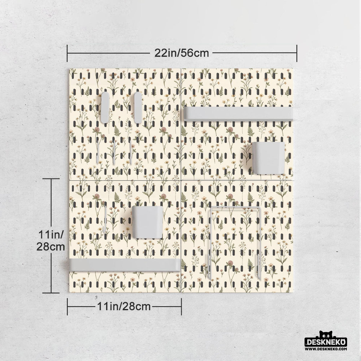 Cream pegboard wall organizer with small floral print, sage green stems, black slot layout, shelves, hooks, clips, and containers.