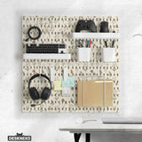 Cream pegboard wall organizer with small floral print, sage green stems, black slot layout, shelves, hooks, clips, and containers.