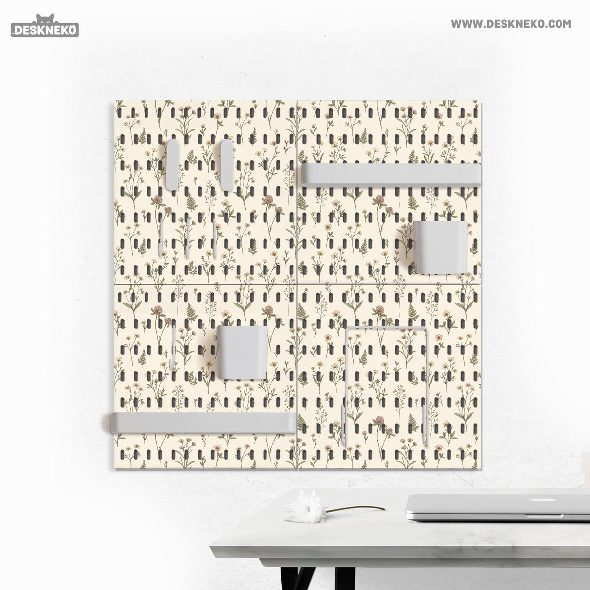 Cream pegboard wall organizer with small floral print, sage green stems, black slot layout, shelves, hooks, clips, and containers.