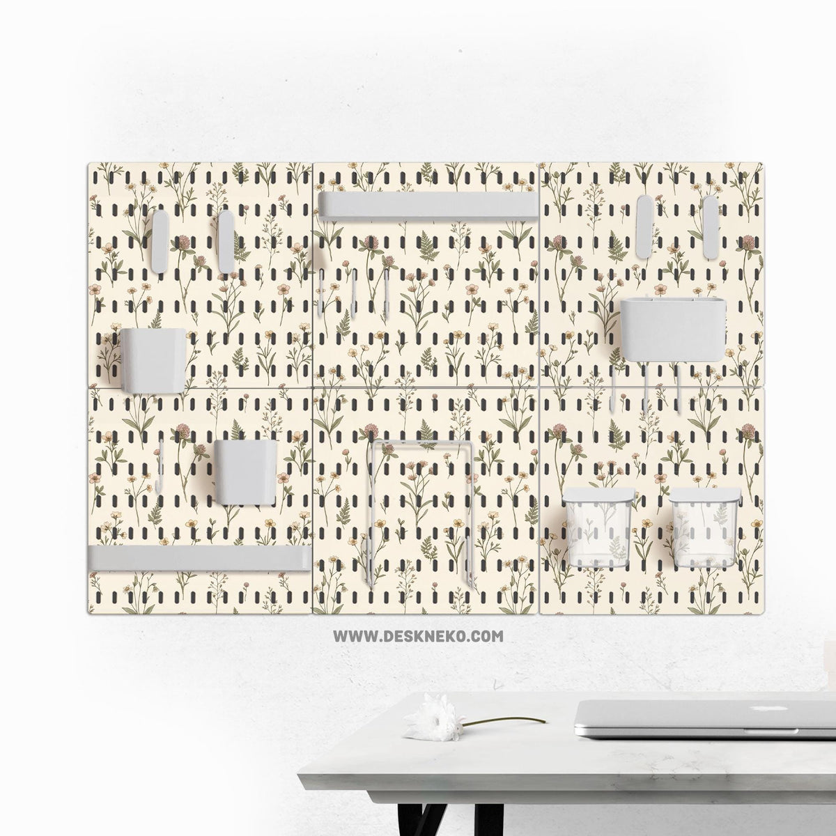 Cream pegboard wall organizer with small floral print, sage green stems, black slot layout, shelves, hooks, clips, and containers.