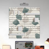 Four pegboard panels in sage green with cream, grey, teal, and leafy botanical artwork arranged in a square layout.