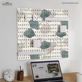 Four pegboard panels in sage green with cream, grey, teal, and leafy botanical artwork arranged in a square layout.