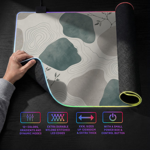 A desk mat with sage green abstract blocks, cream space, gray stone-like shapes, fine topographic contour lines, and small branch details.