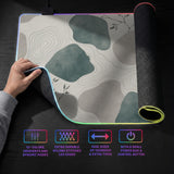 A desk mat with sage green abstract blocks, cream space, gray stone-like shapes, fine topographic contour lines, and small branch details.