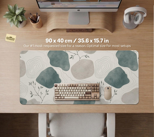 A desk mat with sage green abstract blocks, cream space, gray stone-like shapes, fine topographic contour lines, and small branch details.