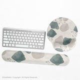 Sage green ergonomic mousepad and keyboard wrist rest with abstract shapes, soft gray details, cream space, topographic contour lines, and leafy branch accents.