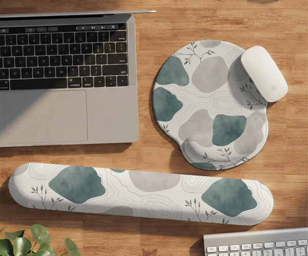 Sage green ergonomic mousepad and keyboard wrist rest with abstract shapes, soft gray details, cream space, topographic contour lines, and leafy branch accents.