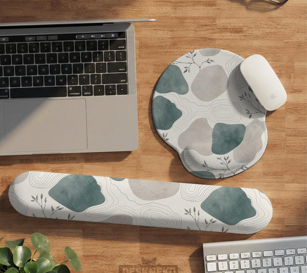 Sage green ergonomic mousepad and keyboard wrist rest with abstract shapes, soft gray details, cream space, topographic contour lines, and leafy branch accents.