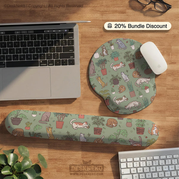 Sage green desk mat with a pattern of lounging cats, leafy plants, cactus pots, and earthy botanical details.
