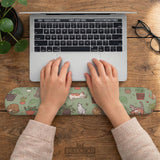 Sage green desk mat with a pattern of lounging cats, leafy plants, cactus pots, and earthy botanical details.