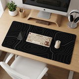 Black desk mat with a thin gray topographic contour line pattern.