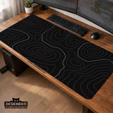 Black desk mat with a thin gray topographic contour line pattern.