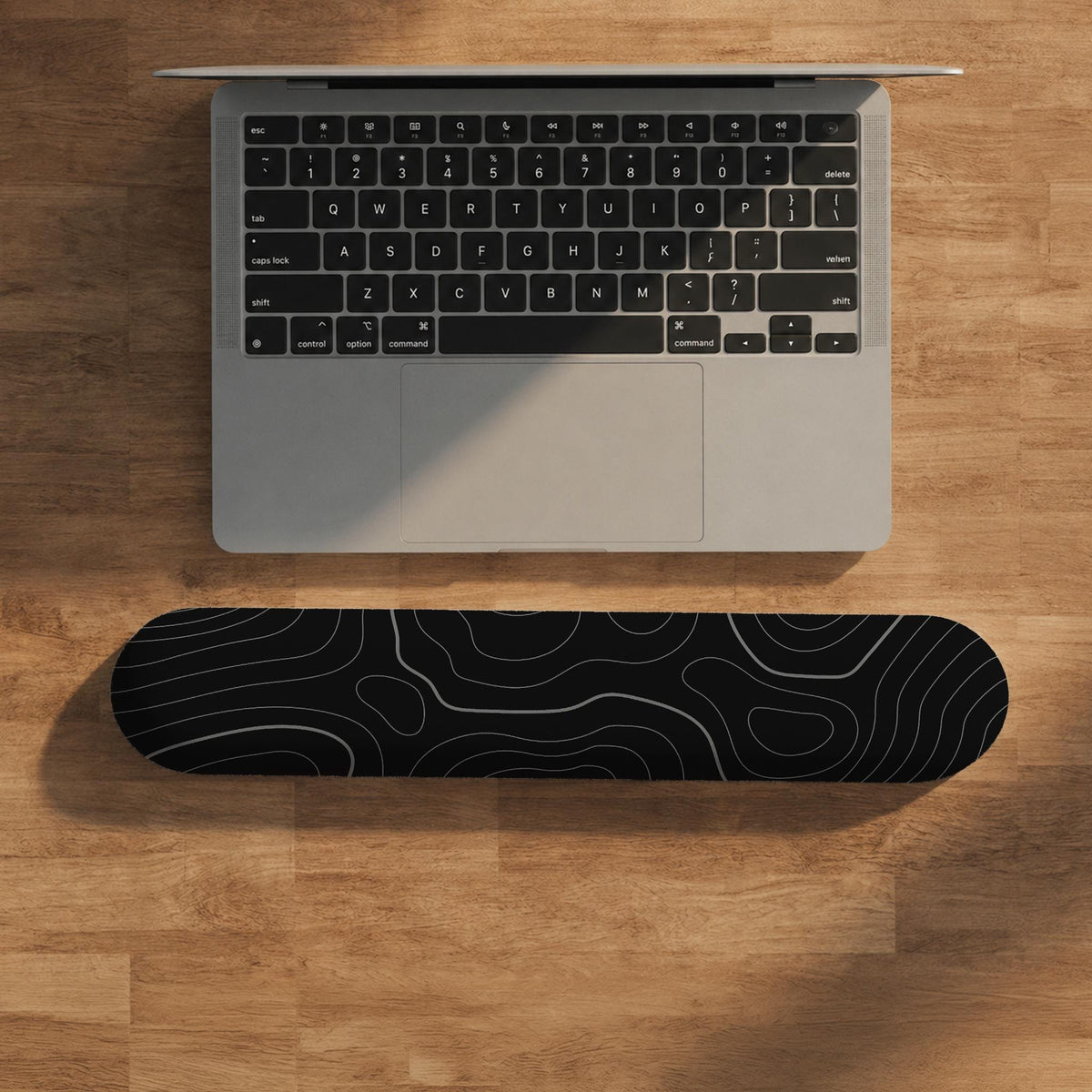 Black mousepad with a gray topographic contour line pattern shown with matching keyboard wrist rest options.