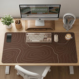 Brown desk mat with a repeating topographic contour line pattern in a neutral earth tone design.