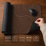 Brown desk mat with a repeating topographic contour line pattern in a neutral earth tone design.