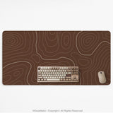 Brown desk mat with a repeating topographic contour line pattern in a neutral earth tone design.