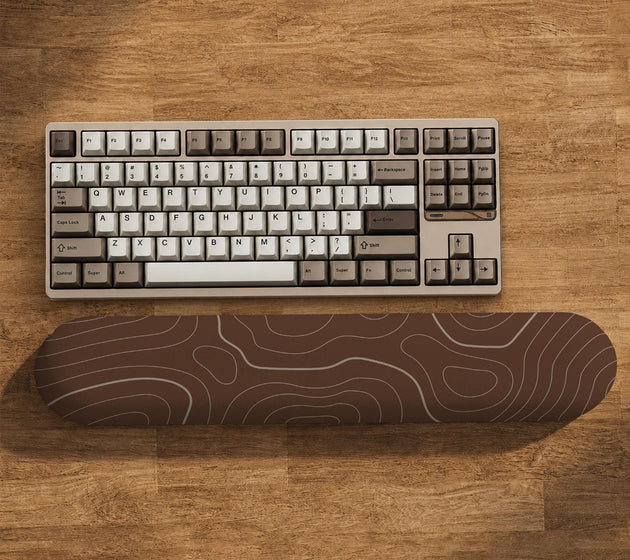 Brown mousepad and keyboard wrist rest with a topographic contour-line pattern.