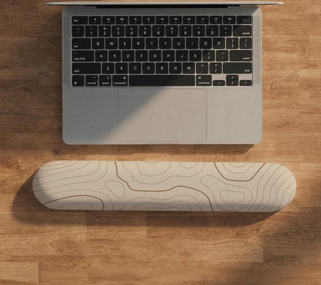 Beige mousepad and keyboard wrist rest with a topographic line pattern shown in a neutral desk setup.