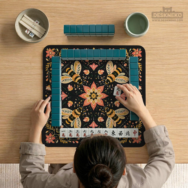 Black mahjong mat with a symmetrical botanical design, coral flowers, golden leaves, and small bees.
