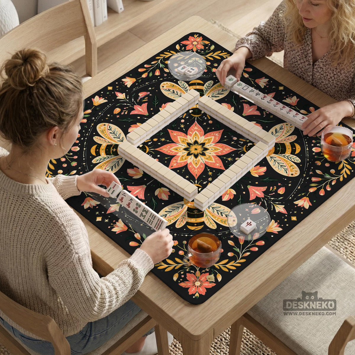 Black mahjong mat with a symmetrical botanical design, coral flowers, golden leaves, and small bees.