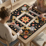 Black mahjong mat with a symmetrical botanical design, coral flowers, golden leaves, and small bees.