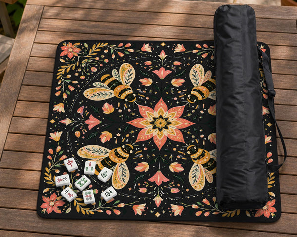 Black mahjong mat with a symmetrical botanical design, coral flowers, golden leaves, and small bees.