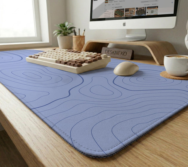 A pastel blue mousepad with an abstract topographic contour line pattern.