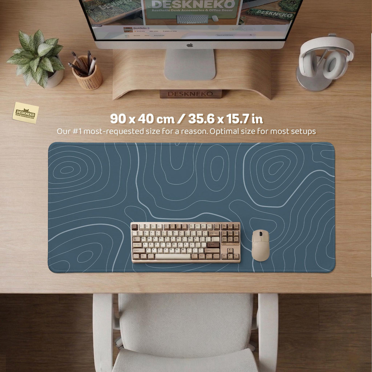 A slate blue desk mat with thin contour line map art on a light background.