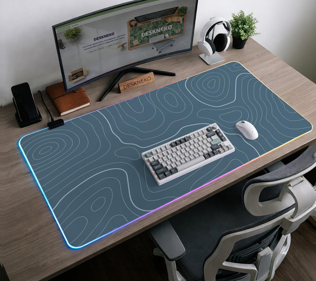 A slate blue desk mat with thin contour line map art on a light background.