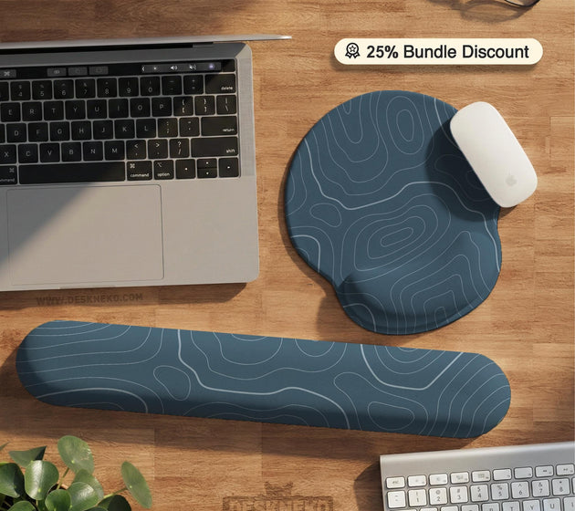 Muted blue desk mat with thin topographic line art pattern shown with matching mousepad and keyboard wrist rest options.