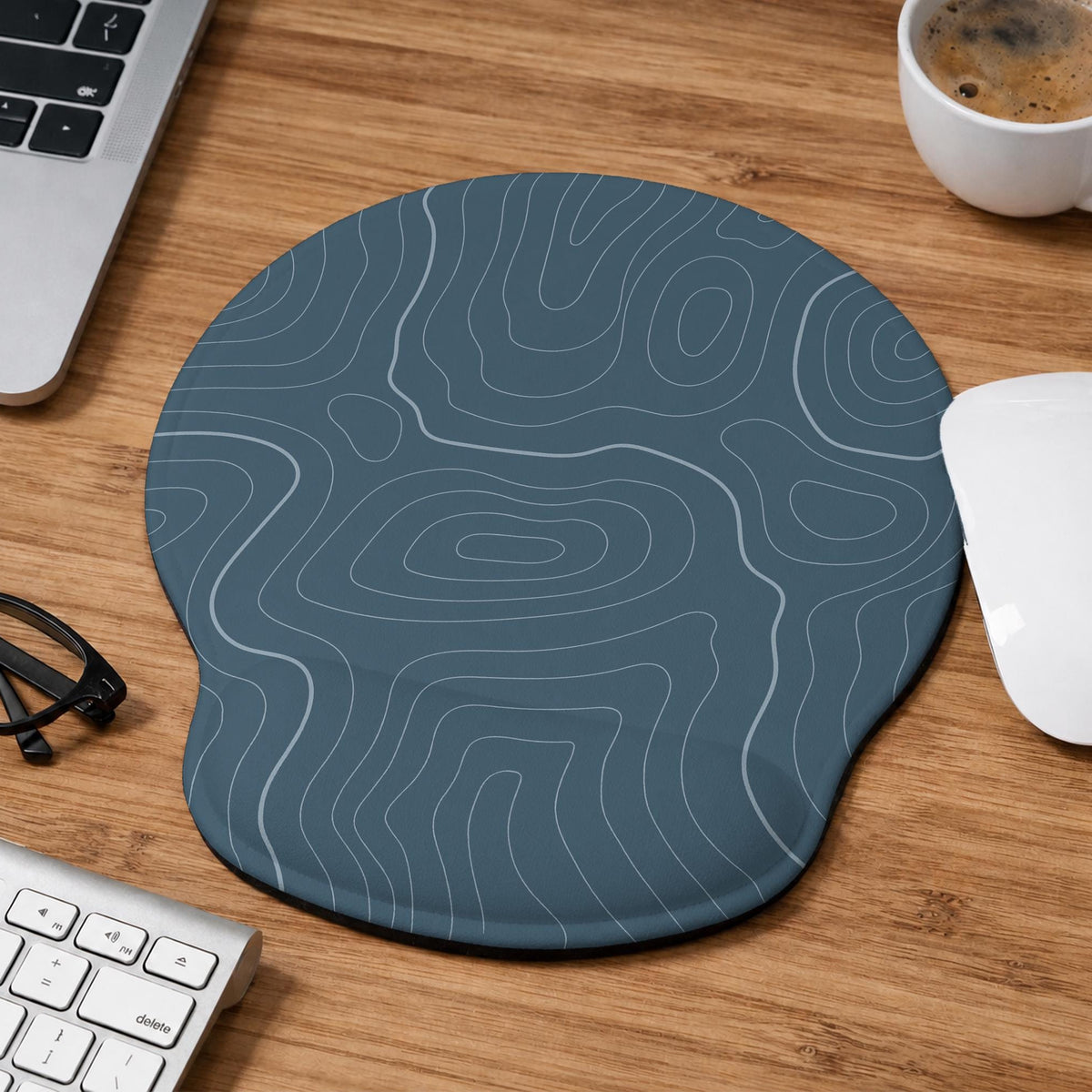 Muted blue desk mat with thin topographic line art pattern shown with matching mousepad and keyboard wrist rest options.