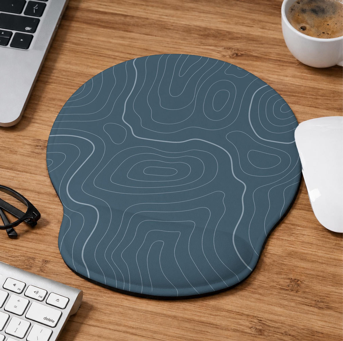 Muted blue desk mat with thin topographic line art pattern shown with matching mousepad and keyboard wrist rest options.