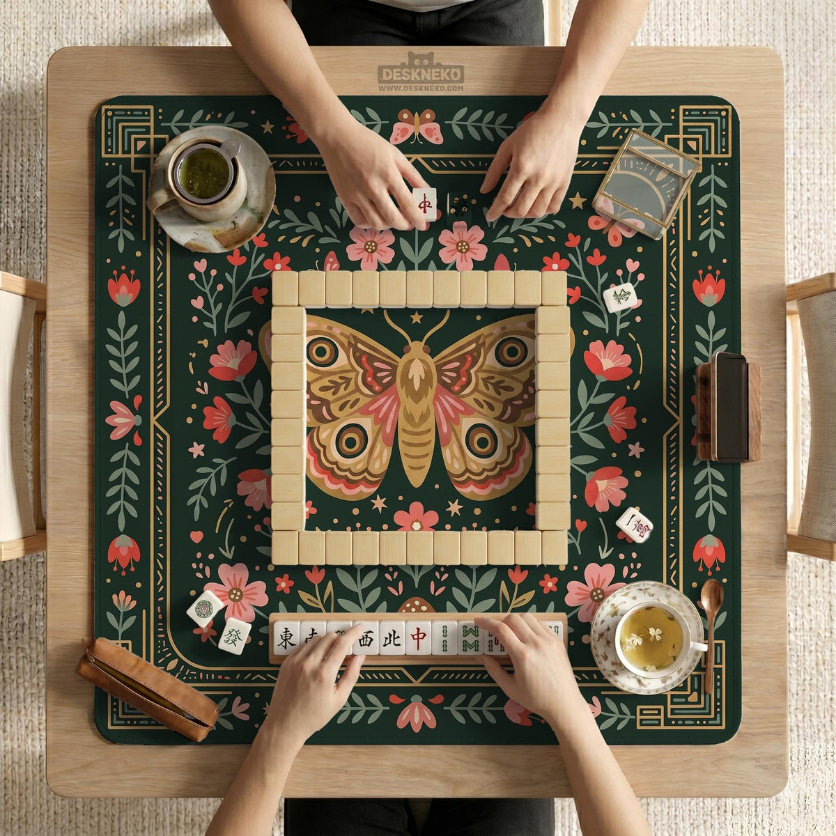 Dark green square mahjong mat with floral branches, small red blossoms, gold line details, and a large moth in the center.