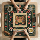 Dark green square mahjong mat with floral branches, small red blossoms, gold line details, and a large moth in the center.