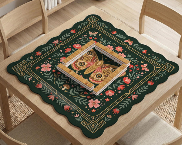Dark green square mahjong mat with floral branches, small red blossoms, gold line details, and a large moth in the center.