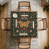 Dark green square mahjong mat with floral branches, small red blossoms, gold line details, and a large moth in the center.