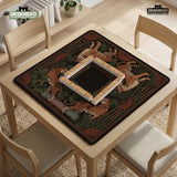Black square mahjong mat with mirrored tiger faces, bamboo, dark tropical leaves, ornate border details, and orange accents.