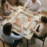 Ivory square mahjong mat with watercolor koi fish, lotus flowers, peach blossoms, sage leaves, and a thin gold border.