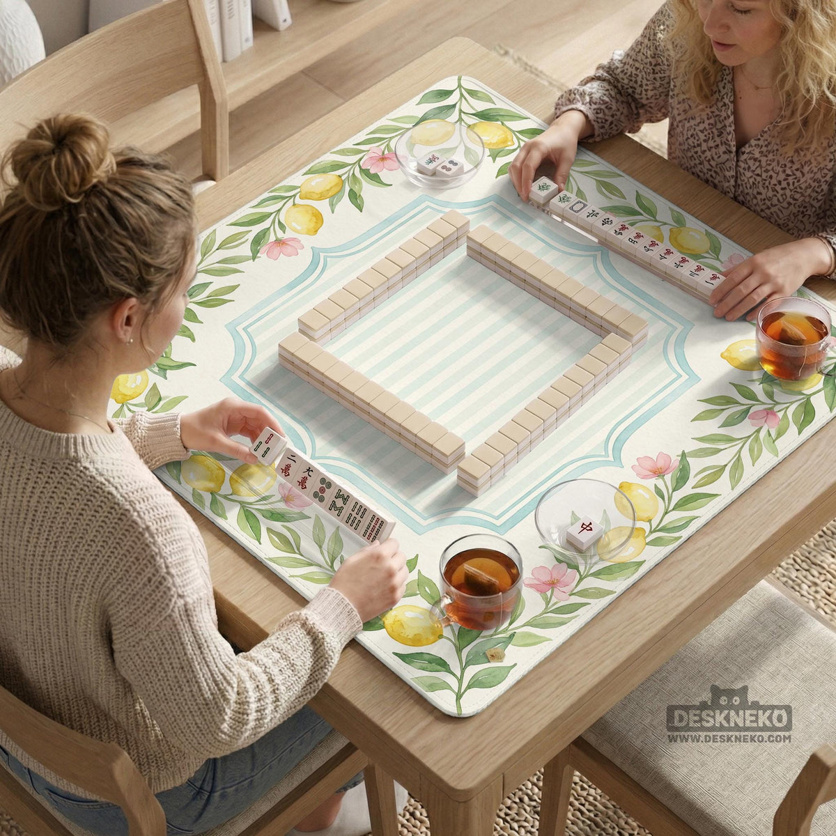 Square yellow mahjong mat with a citrus garden border, green vines, pink blossoms, aqua accents, and a plain center play area.