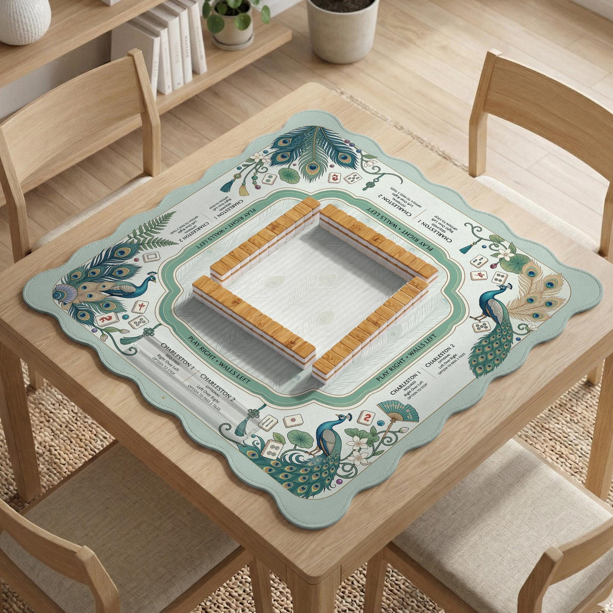 Teal square mahjong mat with peacock feathers, soft floral pattern, tassel details, and printed rule guide text in the center.