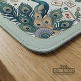 Teal square mahjong mat with peacock feathers, soft floral pattern, tassel details, and printed rule guide text in the center.